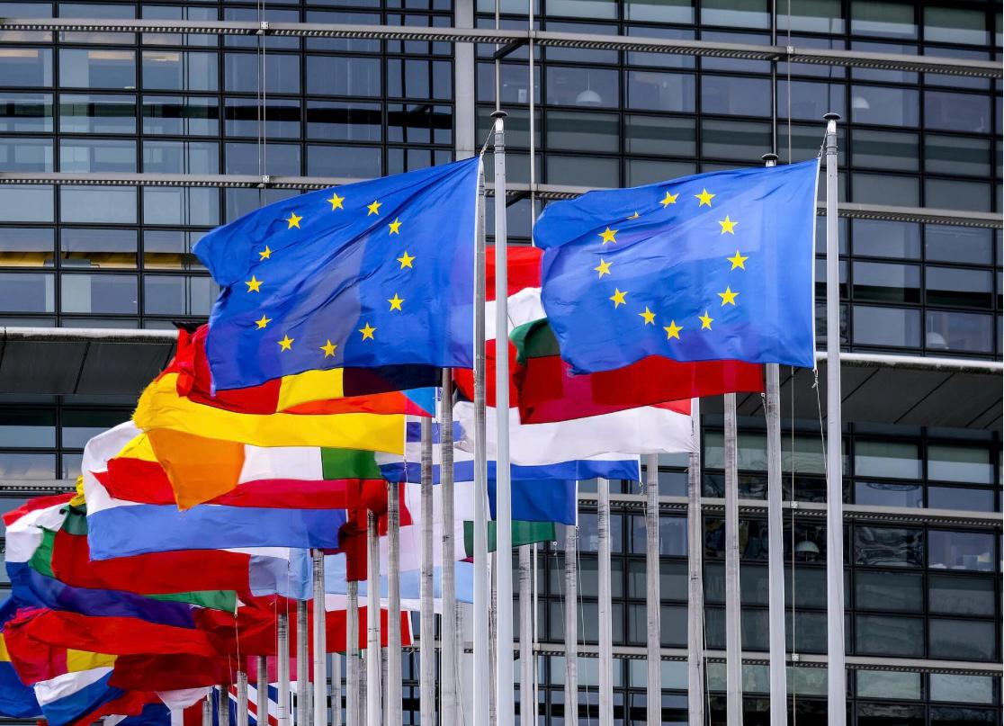 European Union flags waving in front of a modern building in Geneva, Switzerland, symbolizing international cooperation and diplomacy for the NYGC Global Exchange Program.